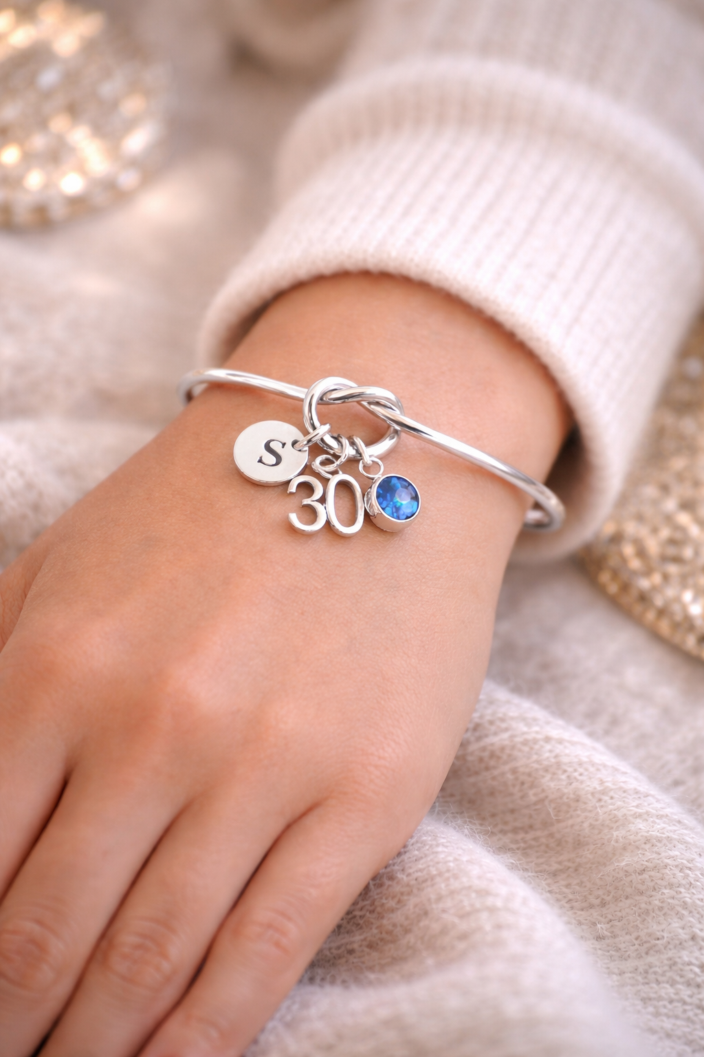 Silver bracelet with charms on a wrist against a soft background