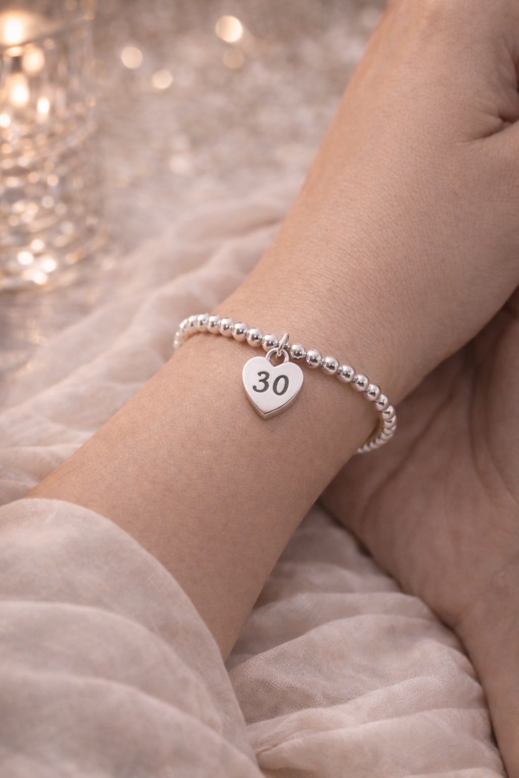 Close-up of silver bracelet with heart charm engraved 30